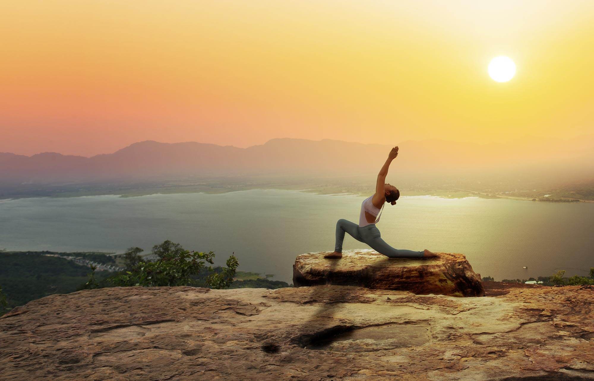 Foto: Frau praktiziert Yoga auf einem Hügel mit Sonnenaufgang im Hintergrund